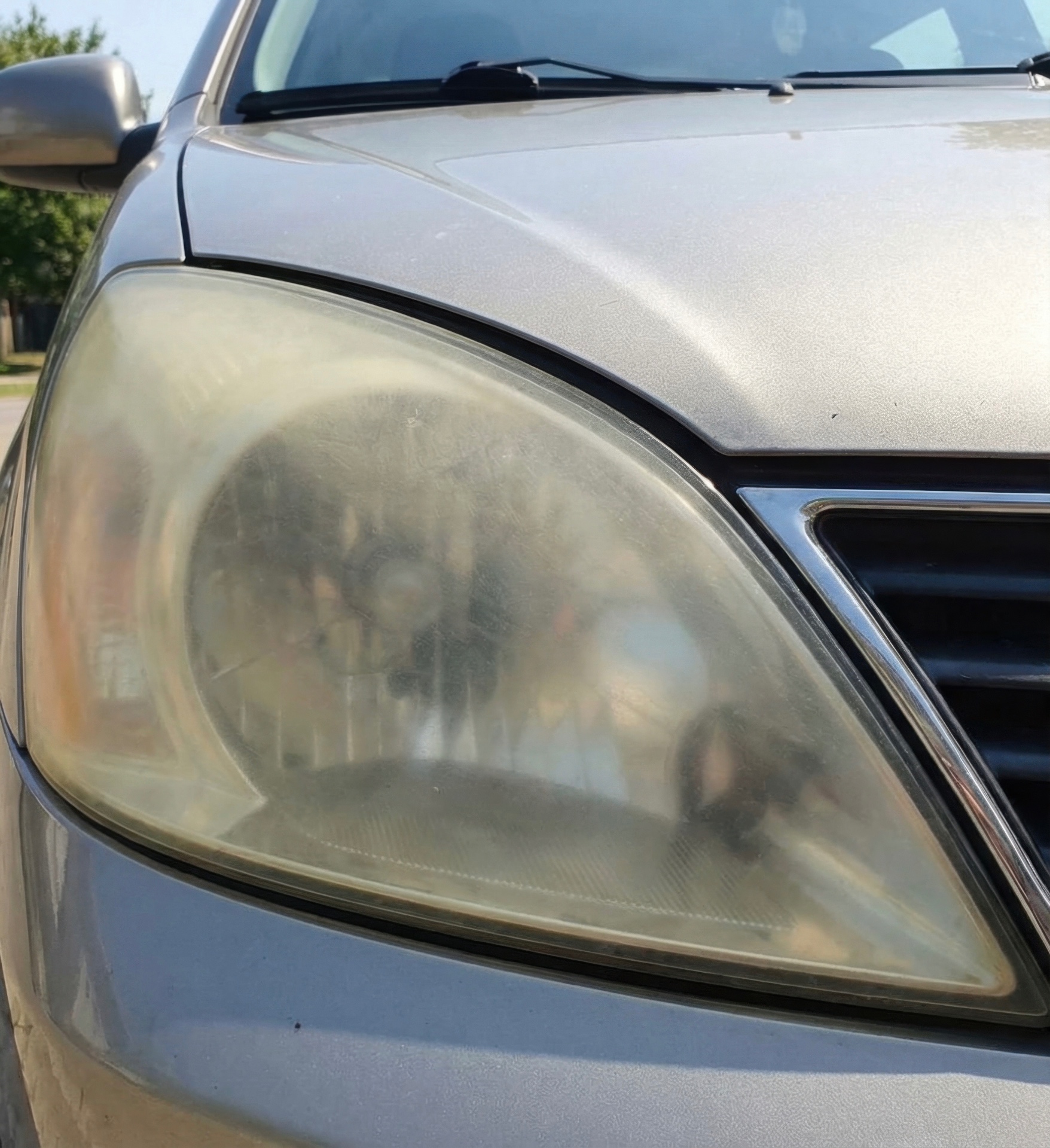 Hazy, oxidized headlight on a silver SUV before SFV Headlights restoration
